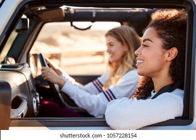 Two Young Female Friends Driving A Car In The Sun, Side View