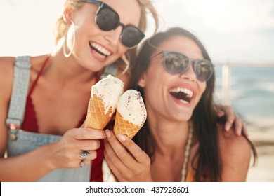 Two young female friends having fun and eating ice cream. Cheerful young women eating icecream outdoors. - Powered by Shutterstock