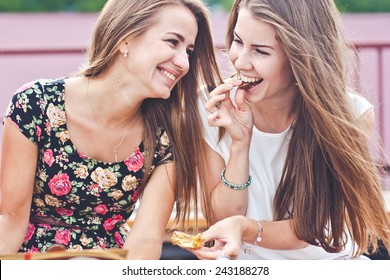 Two young female friends laugh and eat chocolate outdoors  - Powered by Shutterstock