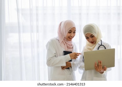 Two young female Muslim doctors are working and discussing using laptop and tablet at the hospital office room. - Powered by Shutterstock