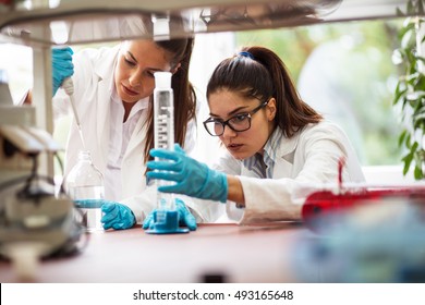 Two Young Female Scientist Doing Experiments In Lab.