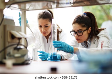 Two Young Female Scientist Doing Experiments In Lab.