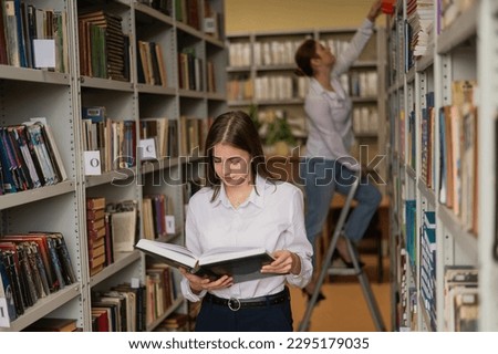 Two young female students in a public library. 