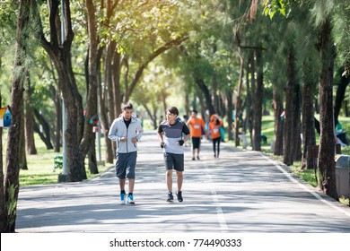 Two Young Fitness Man Running At Morning In The Garden, Park