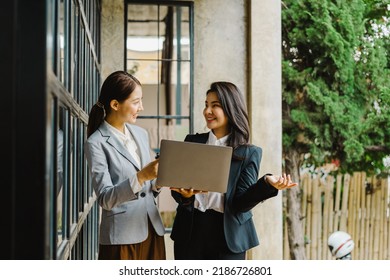 Two young friends of business woman standing and talking during lunch break front office. - Powered by Shutterstock