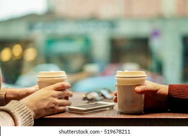 Two young friends drinking coffee in paper take away cup - People having a break sitting in bar restaurant toasting cappuccino - Winter concept - Focus on man hand - Soft saturated retro filter - Powered by Shutterstock