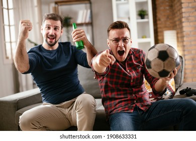 Two young friends enjoying at home. Men drinking beer and watching sports game on tv.	 - Shutterstock ID 1908633331
