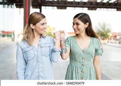 Two Young Friends Looking Happy Face To Face And Wearing Matching Bracelets 