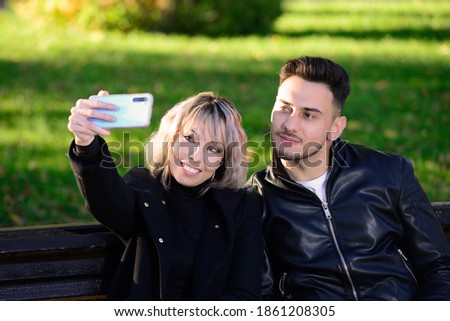 Two young friends in a park taking a selfie with the mobile