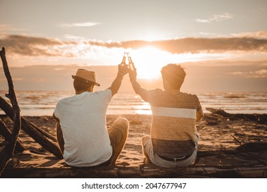 Two young friends spending time together sitting on the beach, drinking beer and toasting on vacation in twilight summer sunset. Friendship concept - Powered by Shutterstock