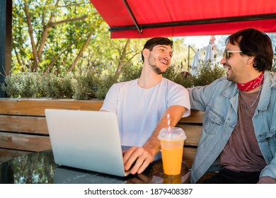 Two Young Friends Using Laptop At Coffee Shop.