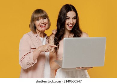 Two Young Fun Happy Smiling Daughter Mother Together Couple Women Wearing Casual Clothes Hold Use Work Point Index Finger On Laptop Pc Computer Show Thumb Up Isolated On Plain Yellow Background Studio