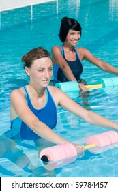 Two Young Girl Doing Aqua Gym Exercise With Water Dumbbell In A Swimming Pool