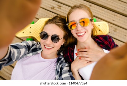 Two young girl in hipster outfit making selfie while lying with on wooden pier - Powered by Shutterstock