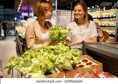 zwei junge Mädchenschwestern kaufen in einem Supermarkt, der Obst und Gemüse schlägt