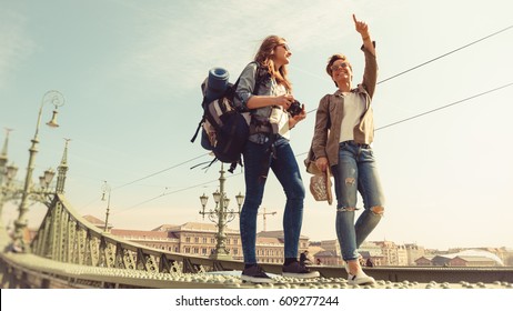 Two young girlfriends traveling, walking on a bridge, enjoying the sunny day and the sightseeing of the city - Shutterstock ID 609277244