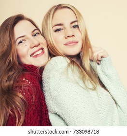 Two Young Girlfriends In Winter Sweaters Indoors Having Fun. Lifestyle. Blond Teen Friends Close Up