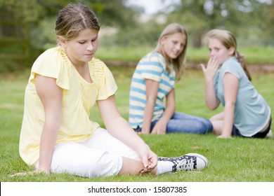 Two young girls bullying other young girl outdoors