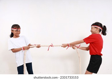 Two young girls celebrating Indonesia independence day with tug of war game. Isolated on white - Shutterstock ID 2331733153