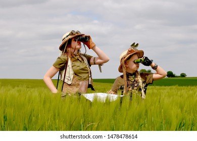 Two young girls dress up as explorers.They pose in 
a prairie grassland countryside dressed with jungle 
hats and khaki safari clothes.