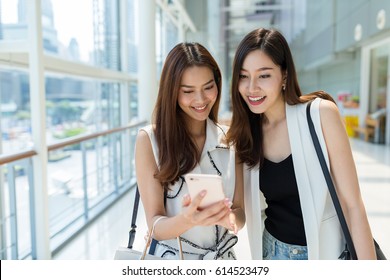 Two Young Girls Go Shopping Together And Using Mobile Phone