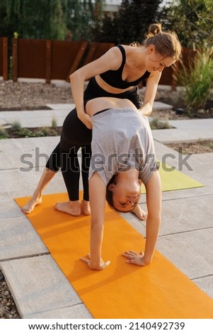 Two young girls practicing stretching and yoga workout exercise together on the terrace