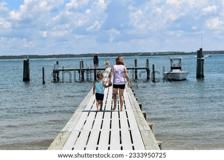 Two young girls standing on a pier in the blue ocean. 