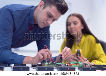 Two young handsome engineers working on electronics components.Tech tests electronic equipment in service center. Technologically Advanced Scientific Research Center.