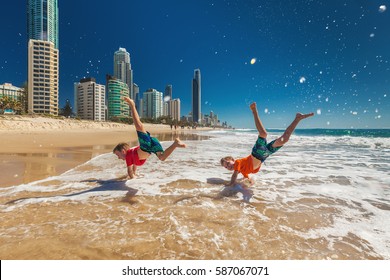 Two young happy boys doing hand stands on Gold Coast beach, Australia