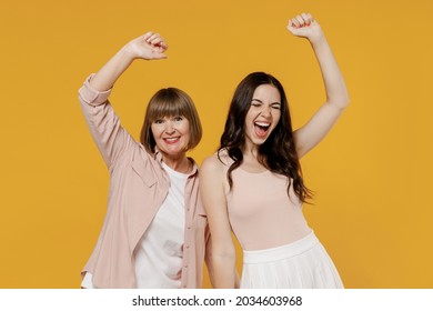 Two Young Happy Daughter Mother Together Couple Women In Casual Beige Clothes Do Winner Gesture Clench Fist With Raised Up Hands Isolated On Plain Yellow Background Studio Family Lifestyle Concept.