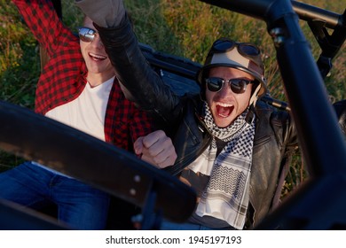 two young happy excited men enjoying beautiful sunny day while driving a off road buggy car - Shutterstock ID 1945197193