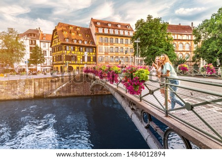 Two young happy girl friends standing on a bridge in Strasbourg while travelling in Petit France region. Tourism and friendship concept