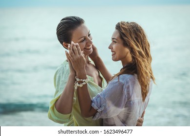 Two young happy women are enjoying in summer day. They are hugging and looking each other with smile.