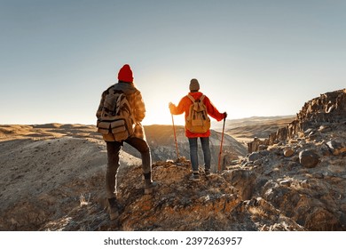 Two young hikers girls are standing at sunset cliff and looks at the view - Powered by Shutterstock