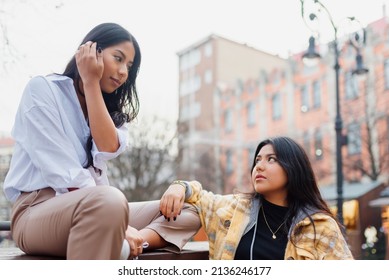 Two Young Hispanic Sisters Look At Each Other Complacently. Family And Friendship. Emotions And Feelings