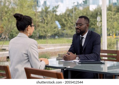 Two Young Intercultural Business Partners In Formalwear Negotiating At Outdoor Meeting