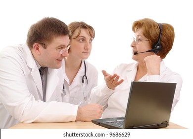 Two young interns consulting medical problem with senior doctor wearing headset sitting behind desk with laptop over white
