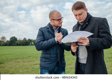 Two Young Investors Are Having A Business Meeting Outside. Field Background.