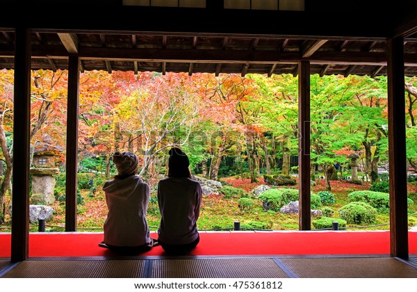 两个年轻的日本女孩坐在红地毯地板上 看到和欣赏秋天丰富多彩的树叶日本庭园 京都 日本 这里是临宰禅教派 在秋季非常有名 库存照片 立即编辑