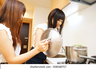 Two young Japanese women cooking in kitchen