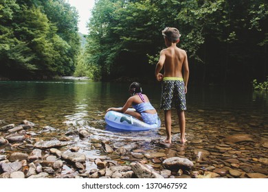 Two Young Kids Look Out At A Swimming Hole.