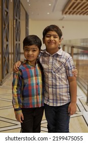 Two Young Kids, Standing Together Posing For The Camera In Button Down Shirt