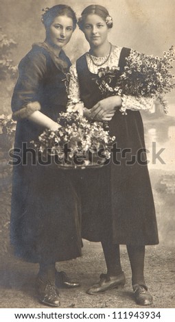 two young ladies with flowers. vintage picture ca. 1920