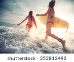 Two young ladies surfers running into the sea with surf boards