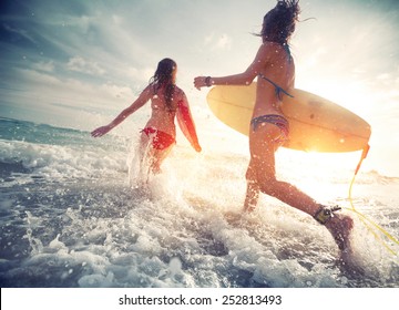 Two young ladies surfers running into the sea with surf boards - Shutterstock ID 252813493