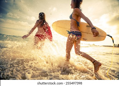 Two young ladies surfers running into sea with surf boards - Powered by Shutterstock