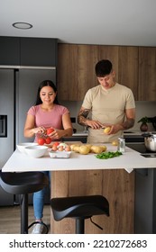 Two Young Latin People Cooking Together At Kitchen.