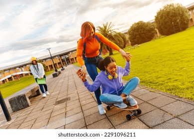 two young latina girls having fun skateboarding after school. Unity and friendship. end of school classes and vacations. - Powered by Shutterstock