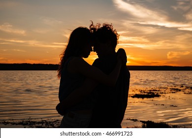 Two young lovers standing on a beach and looking at each other on sunset background స్టాక్ ఫోటో