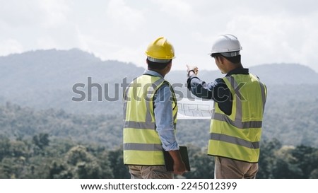 Two young maintenance engineer man working with blueprint on the mountain, Environmental engineering concept.
